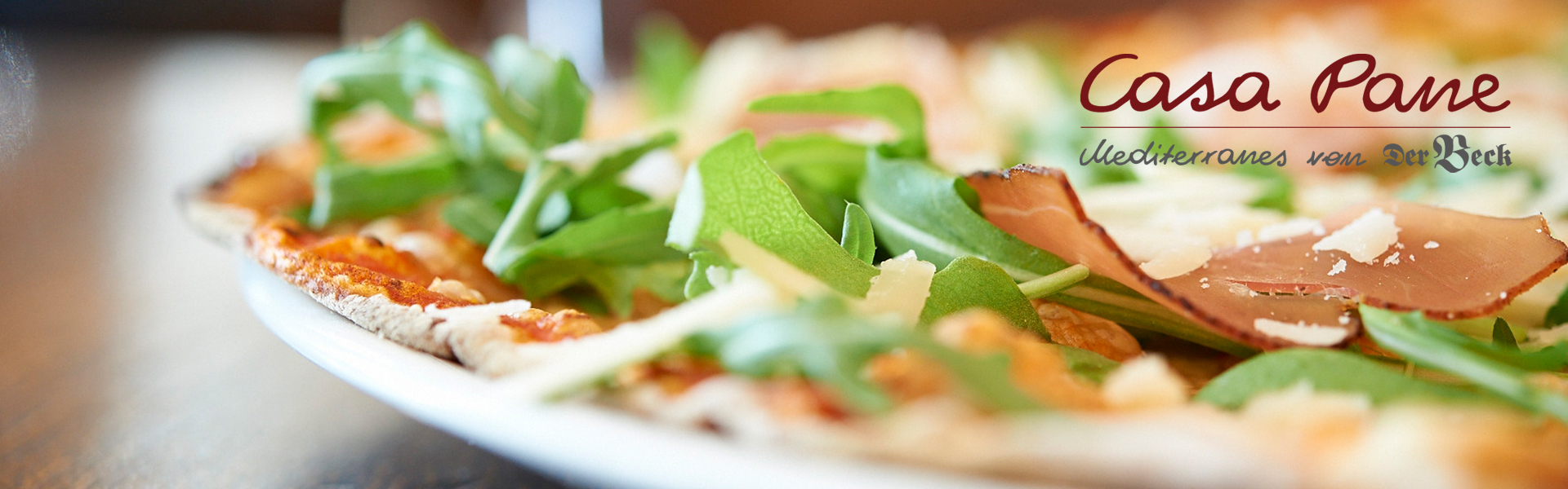 Nahaufnahme einer Pizza mit Rucola, Schinken und Parmesan